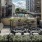 a courtyard with chairs and plants in it and buildings around it