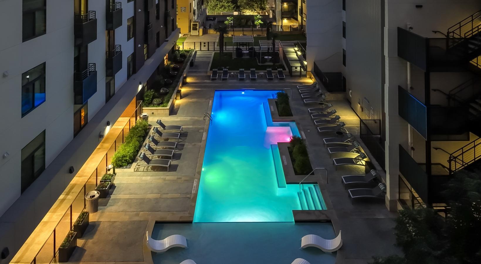 Relax and unwind poolside a pool in a courtyard between buildings