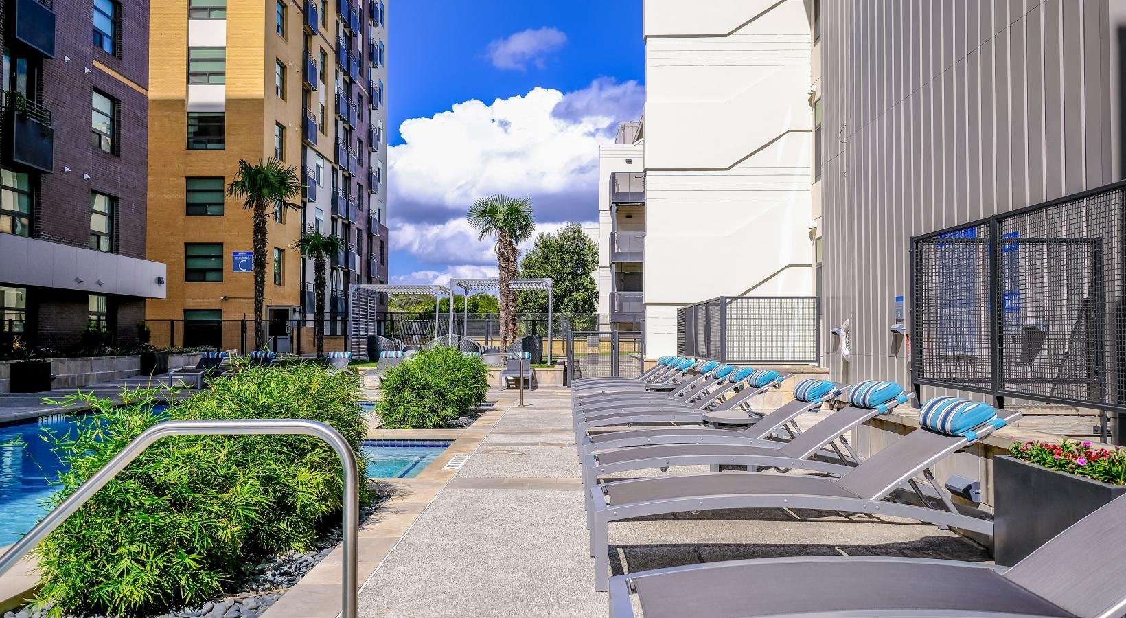 Relax and unwind poolside a patio with chairs and tables by a pool and buildings